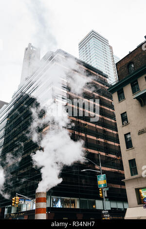 New York City, USA - June 24, 2018: Low angle view of steam coming out stack for venting the district heating system in Midtown of New York Stock Photo