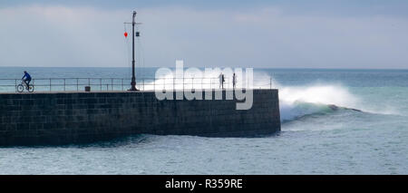 Rough seas hitting the harbour wall at Porthleven, Cornwall and soaking the onlookers in big waves. Stock Photo
