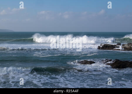 Dramatic breaking waves pounding towards the shore near Godrevy, Cornwall in bright sunshine, the wind blowing spray from the crests. Stock Photo