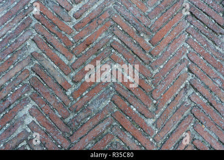 Mossy diagonal pattern of brick pavement in a herringbone style for background, Old orange bricks tiled floor with zigzag pattern. Stock Photo