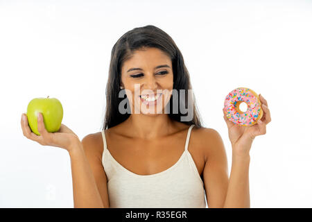 Beautiful happy young woman holding apple and doughnut in healthy unhealthy food, detox eating, calories and diet concept.. Stock Photo