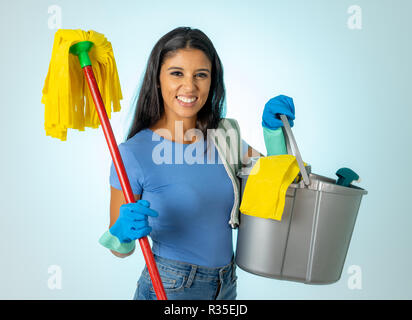 Beautiful happy latin woman holding cleaning equipment in Cleaning service Professional, housemaid and housework isolated on blue background. Stock Photo