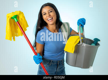 Beautiful happy latin woman holding cleaning equipment in Cleaning service Professional, housemaid and housework isolated on blue background. Stock Photo