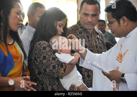 Batam, Indonesia. A priest makes a cross mark on the forehead of baptized child. Stock Photo