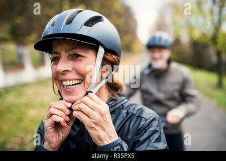 Active senior couple with electrobikes standing outdoors on a road in nature. Stock Photo