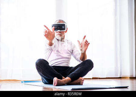 Senior man with VR goggles doing exercise at home. Stock Photo