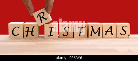 The word "CHRISTMAS" on dices infront of a red background Stock Photo