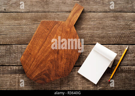 Notepad and chopping board with pencil on wooden table , recipes food or diet plan for healthy habits shot note background concept. Stock Photo