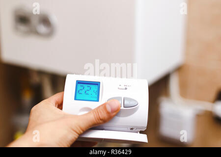 Person near central heating controlling the temperature with a radio device. Person setting the temperature on heating boiler with a radio device. Stock Photo