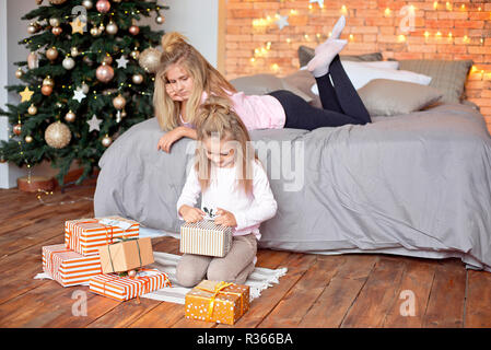 Merry Christmas and Happy Holidays. Cheerful cute children opening gifts. Kids having fun near tree in the morning. Loving family with presents in roo Stock Photo