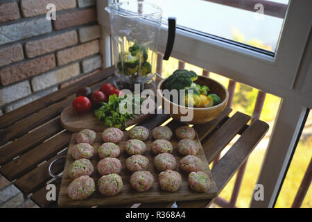 Homemade raw beef meatballs on a pan, before cooking, with vegetables Stock Photo