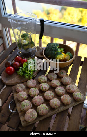 Homemade raw beef meatballs on a pan, before cooking, with vegetables Stock Photo