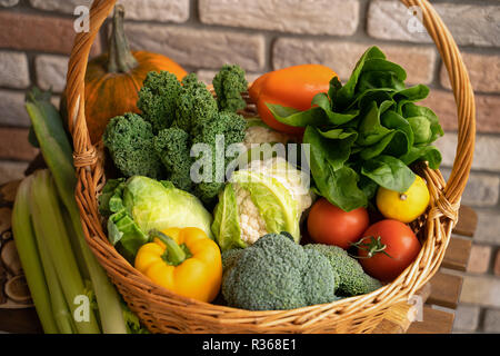 Healthy fresh vegetables and fruits in willow basket on wooden background Stock Photo