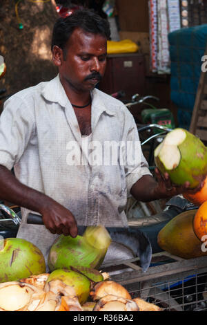 Chennai, India - September 5, 2007: An Indian man cuts a young green coconut with a sharp chopper for coconut water juice in the city-center of Chenna Stock Photo