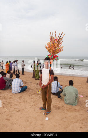 Chennai, India - September 6, 2007: A local boy selling toys and souvenirs poses for a photo at Marina Beach in Chennai as other enjoy themselves Stock Photo