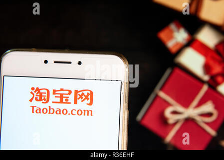 Chinese online shopping website owned by Alibaba Group, Taobao, company logo is seen on an Android mobile device with a Christmas wrapped gifts in the background. Stock Photo