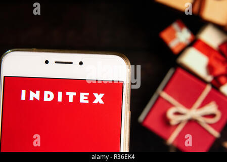 Biggest fashion group in the world Spanish multinational clothing company Inditex logo is seen on an Android mobile device with a Christmas wrapped gifts in the background. Stock Photo