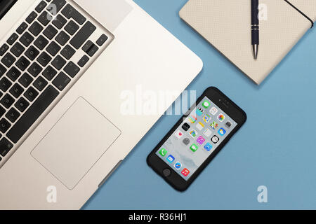 Laptop computer, smart phone and a note book on a blue desk, flat lay. Stock Photo