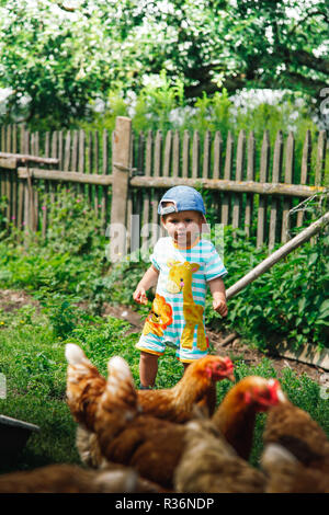 A small child on the farm feeds the chickens bread Stock Photo