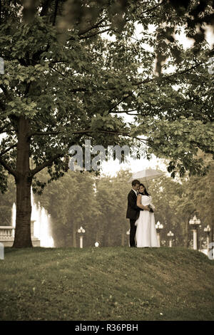 The bride and groom, hugging stand near the tree under a white umbrella,vintage Stock Photo
