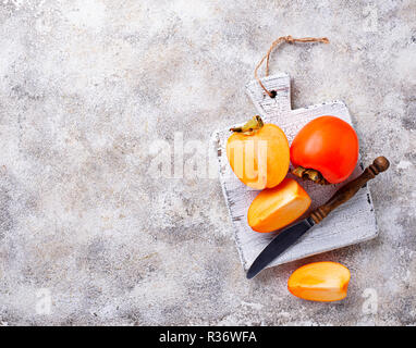 Fresh ripe persimmon on white cutting board Stock Photo