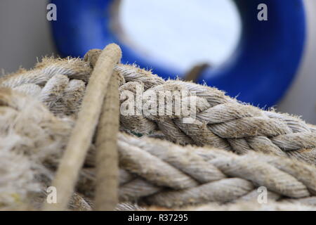 A shot of a rope with a blue ship window on the background Stock Photo