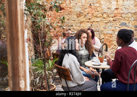 Female friends chatting over coffee in a trendy cafe courtyard Stock Photo