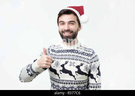 Happy funny man in red christmas hat show thumbs up and good luck. Stock Photo