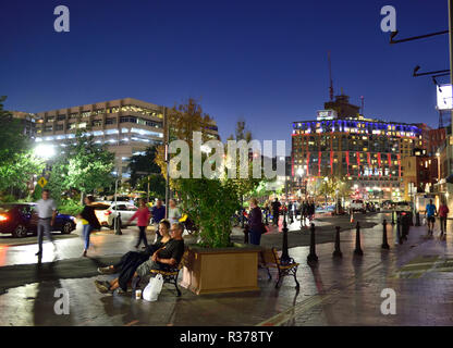 Street scene downtown Boston, Massachusetts, USA, at night with people sitting by Rose Kennedy Greenway Stock Photo