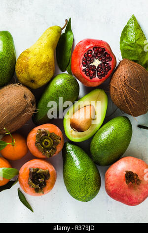 different fruits of pomegranate, pear, mandarin, lemon, avocado and persimmon with coconut on the table. basis of healthy nutrition and daily juices Stock Photo
