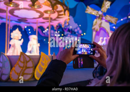 Disney Land Paris, France, November 2018: Woman taking a picture with her smartphone inside Small World a boat ride attraction. Stock Photo