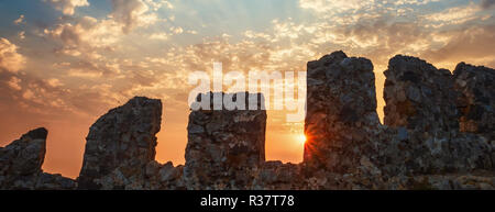 Fortress wall on mountain view of sunset on sea sun rays through clouds. Holiday vacation travel seascape Toned landscape wide angle Stock Photo