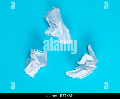 three crumpled white pieces of paper in a cell from a school notebook on a blue background Stock Photo
