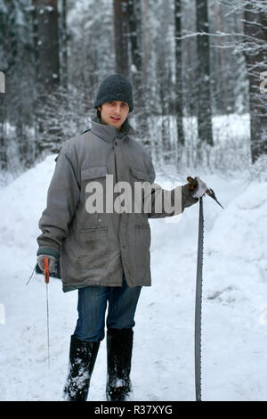 Forest worker is holding two big sharp saws in hands on winter day in the snowy forest Stock Photo