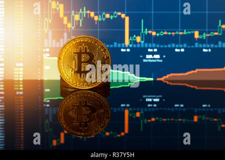 Bitcoin gold coin and defocused chart background. Virtual cryptocurrency concept. Stock Photo