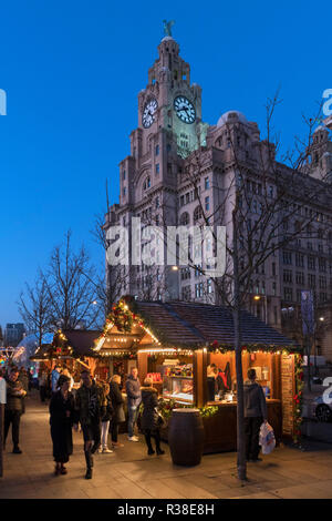 Christmas market stalls at the Christmas Ice Festival fairground with The Liver Building behind, Pier Head, Liverpool, England, UK Stock Photo