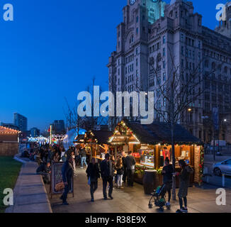 Christmas market stalls at the Christmas Ice Festival fairground with The Liver Building behind, Pier Head, Liverpool, England, UK Stock Photo