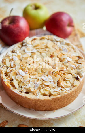 Freshly baked homemade apple pie with almond flakes cake on yellow Stock Photo