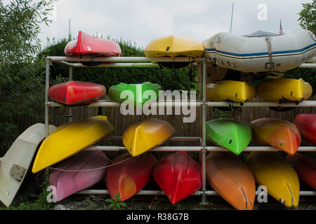 Kayaks on metal rack, wood fence and bushes in background. Essex is a pretty village, white collar executives with beautiful homes. Connecticut River. Stock Photo