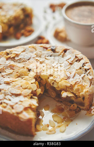 Whole delicious apple cake with almonds served on wooden table Stock Photo