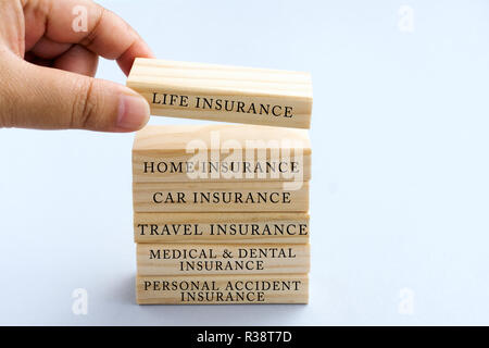 Hand Picking Wood Block with Word Life Insurance. Business Concept Type of Insurances on Wood Top Block with Word: Life, Home, Car, Travel, Medical an Stock Photo