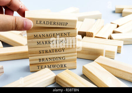 Hand Picking Wood Block with Word Leadership. Business Concept - Wood Top Block with Word: Leadership, Teamwork, Vision, Confidence, Strategy and Mana Stock Photo