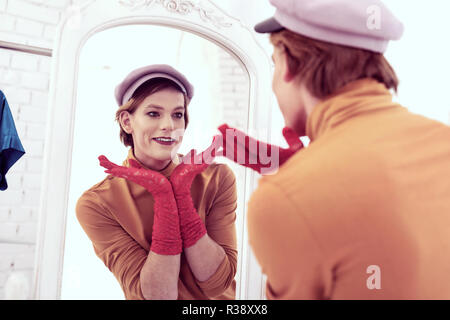 Short-haired queer young man posing against full length mirror Stock Photo