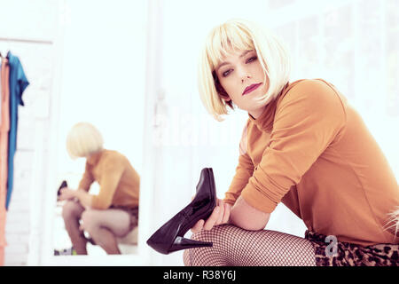 Short-haired blond transgender male in fishnet tights shrewd looking Stock Photo