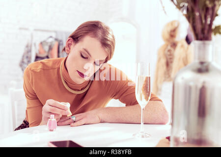 Beautiful short-haired transgender man painting his nail Stock Photo