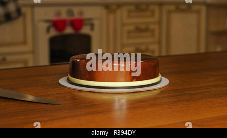 Prague mousse cake. Ready cake on a stand is on the table. A kitchen knife lies nearby. Cooking in a pastry shop. Stock Photo