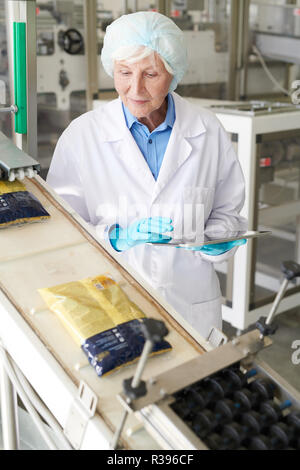 Smiling mature female worker packaging wine bottles Stock Photo - Alamy