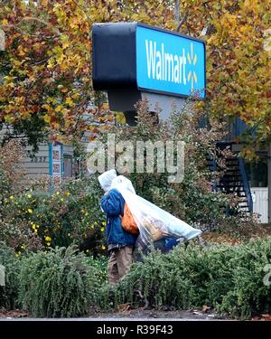 Butte, USA. 21st Nov, 2018. A resident walks in rain at a parking lot in Chico of Butte County, California, the United States, Nov. 21, 2018. Local officials warned that the rain after the wildfire could cause risk of flash floods and mudflows. Credit: Wu Xiaoling/Xinhua/Alamy Live News Stock Photo