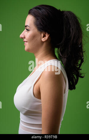 Portrait of beautiful Iranian woman against green background Stock Photo