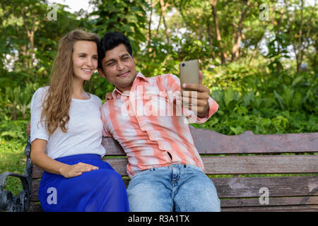 Happy multi ethnic couple smiling while taking selfie picture wi Stock Photo